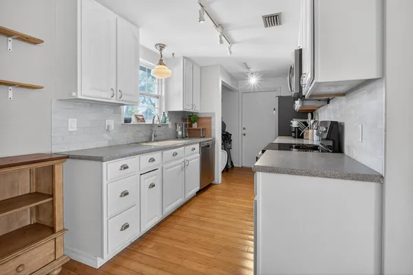 a kitchen with granite countertop a sink a counter top space and cabinets
