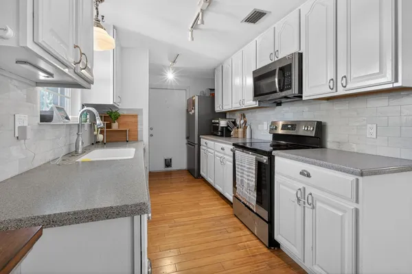 a kitchen with stainless steel appliances granite countertop a refrigerator a stove top oven a sink and dishwasher