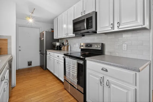 a kitchen with stainless steel appliances granite countertop white cabinets sink and a granite counter top