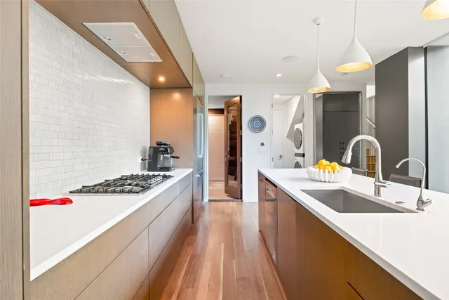 a kitchen with stainless steel appliances kitchen island granite countertop a refrigerator a stove and a dining table with wooden floor