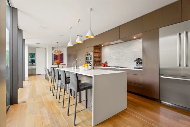 a kitchen with stainless steel appliances kitchen island granite countertop a stove a sink and a dining table with the view of living room