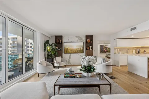 a living room with furniture potted plant and kitchen view
