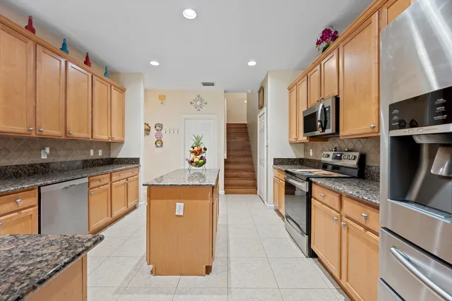 a large kitchen with stainless steel appliances granite countertop a stove top oven a refrigerator a sink and dishwasher