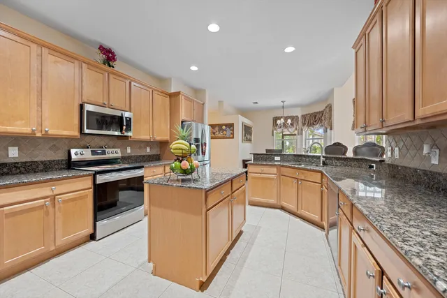 a kitchen with granite countertop a stove top oven a sink dishwasher and a refrigerator with wooden floor