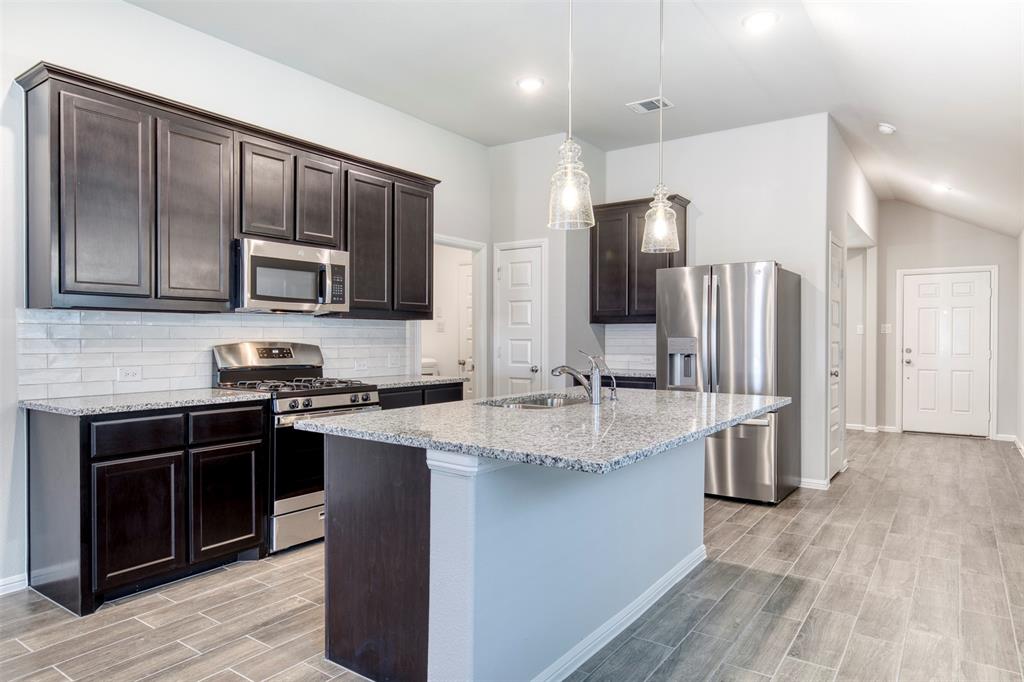 7108 Calshot Road Pilot Point, TX 76258 - Photo 9 of 28 Kitchen features warm wood cabinetry and granite countertops.