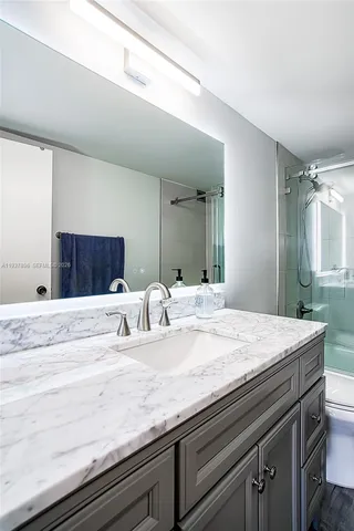 a bathroom with a granite countertop sink and a mirror