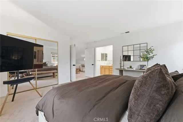 a spacious bedroom with a bed and a flat screen tv