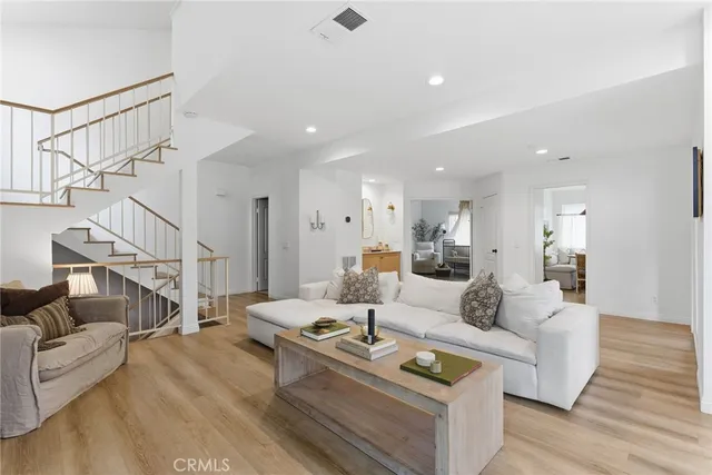 a living room with furniture and a dining table with wooden floor