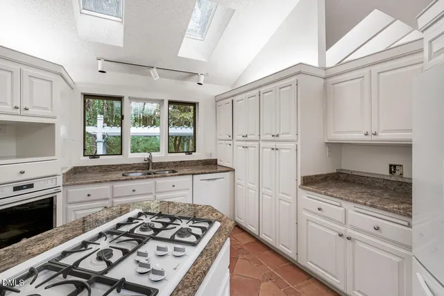 a kitchen with granite countertop white cabinets and a window