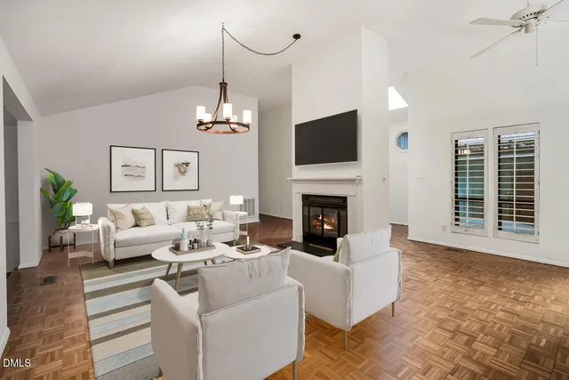 a view of an empty room with chandelier fan and fire place