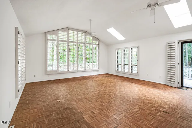 a view of an empty room with a window and a kitchen
