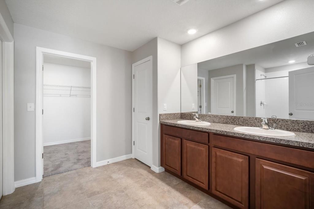 9607 Lemon Drop Loop Ruskin, FL 33573 - Photo 16 of 31 a bathroom with a granite countertop sink and a mirror