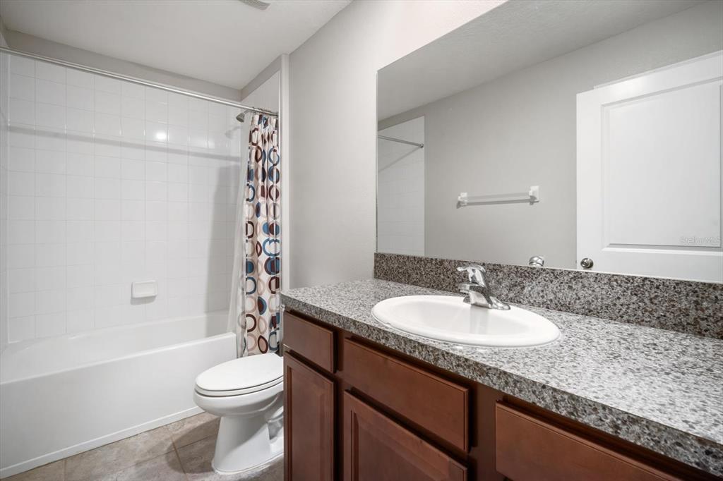 9607 Lemon Drop Loop Ruskin, FL 33573 - Photo 21 of 31 a bathroom with a granite countertop sink a toilet a mirror and bathtub