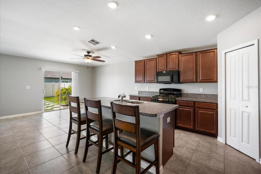 9607 Lemon Drop Loop Ruskin, FL 33573 - Photo 8 of 31 a kitchen with stainless steel appliances granite countertop a stove top oven a sink dishwasher and a refrigerator with wooden cabinets