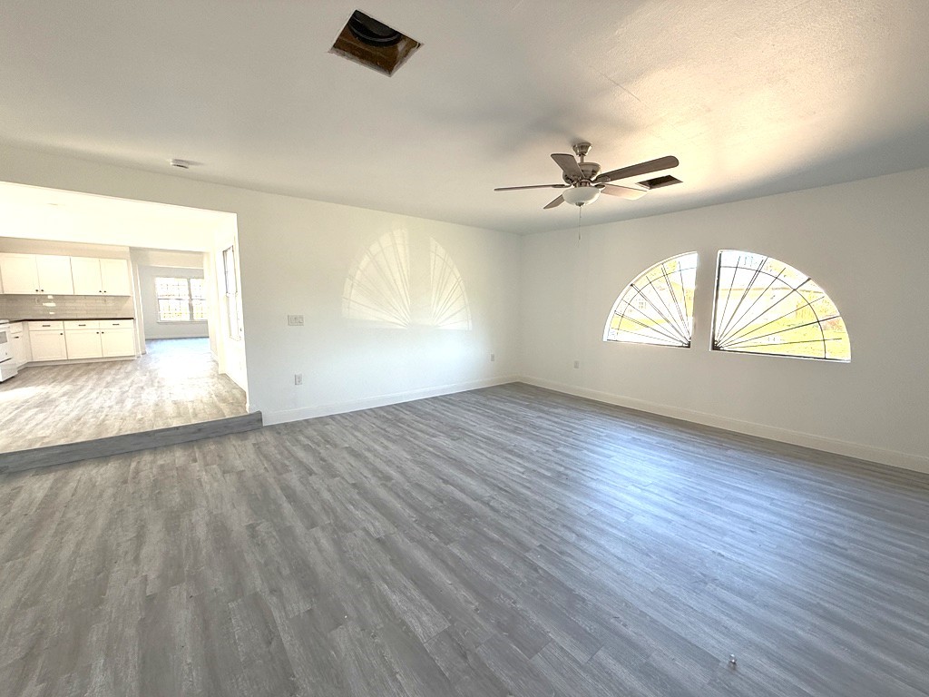 7430 Claiborne Street Houston, TX 77016 - Photo 3 of 23 an empty room with wooden floor chandelier fan and windows