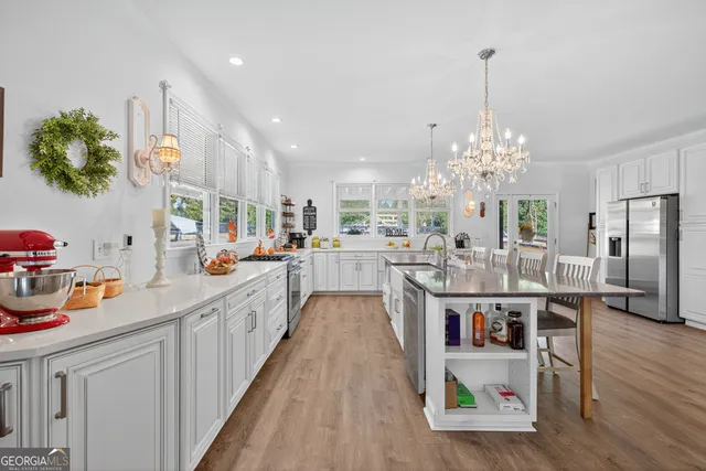 a kitchen with stainless steel appliances kitchen island granite countertop a sink cabinets and wooden floor