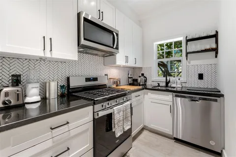 a kitchen with stainless steel appliances granite countertop white cabinets a sink and a stove