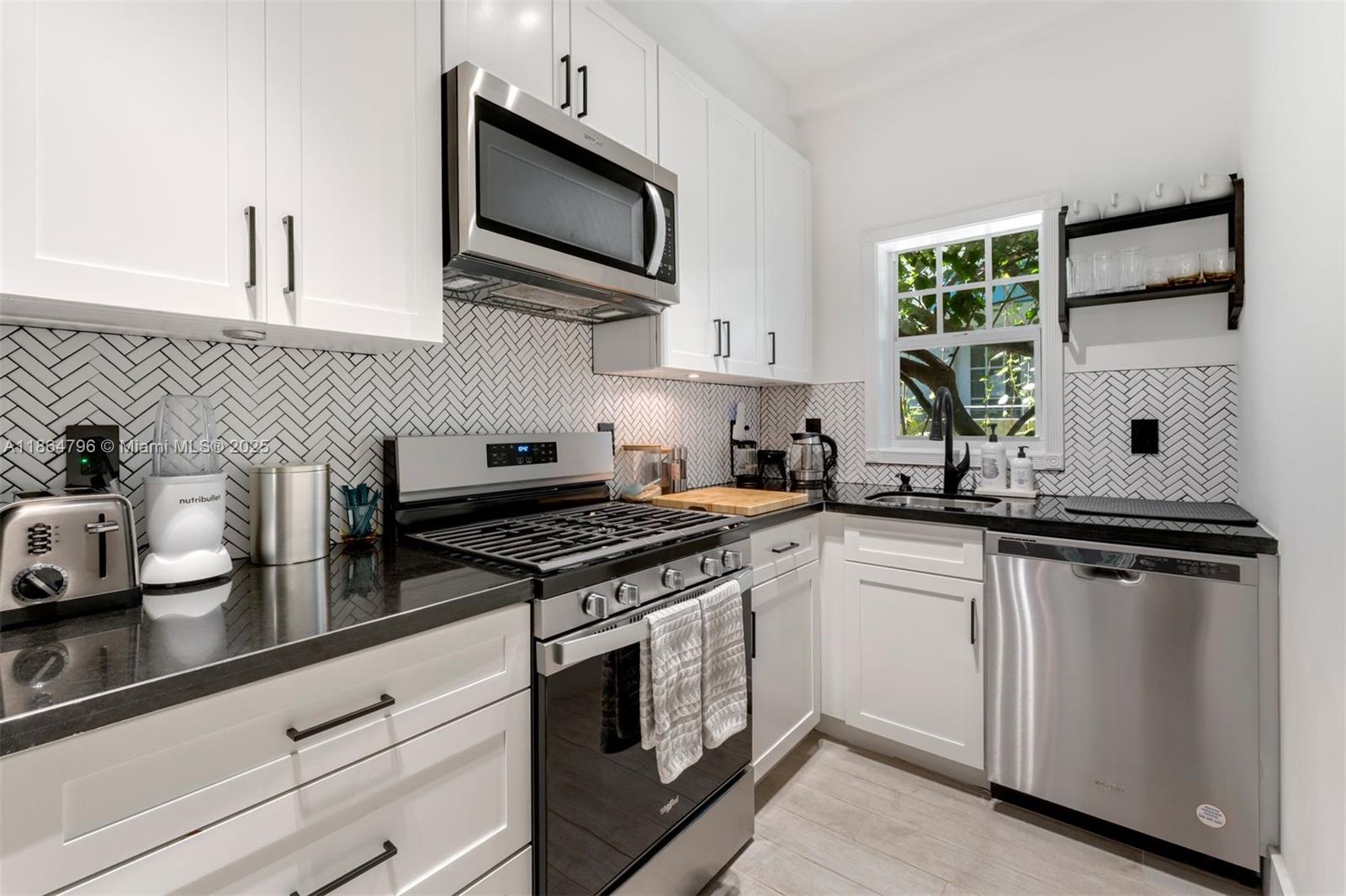 1045 Michigan Avenue, Unit B Miami Beach, FL 33139 - Photo 5 of 15 a kitchen with stainless steel appliances granite countertop white cabinets a sink and a stove