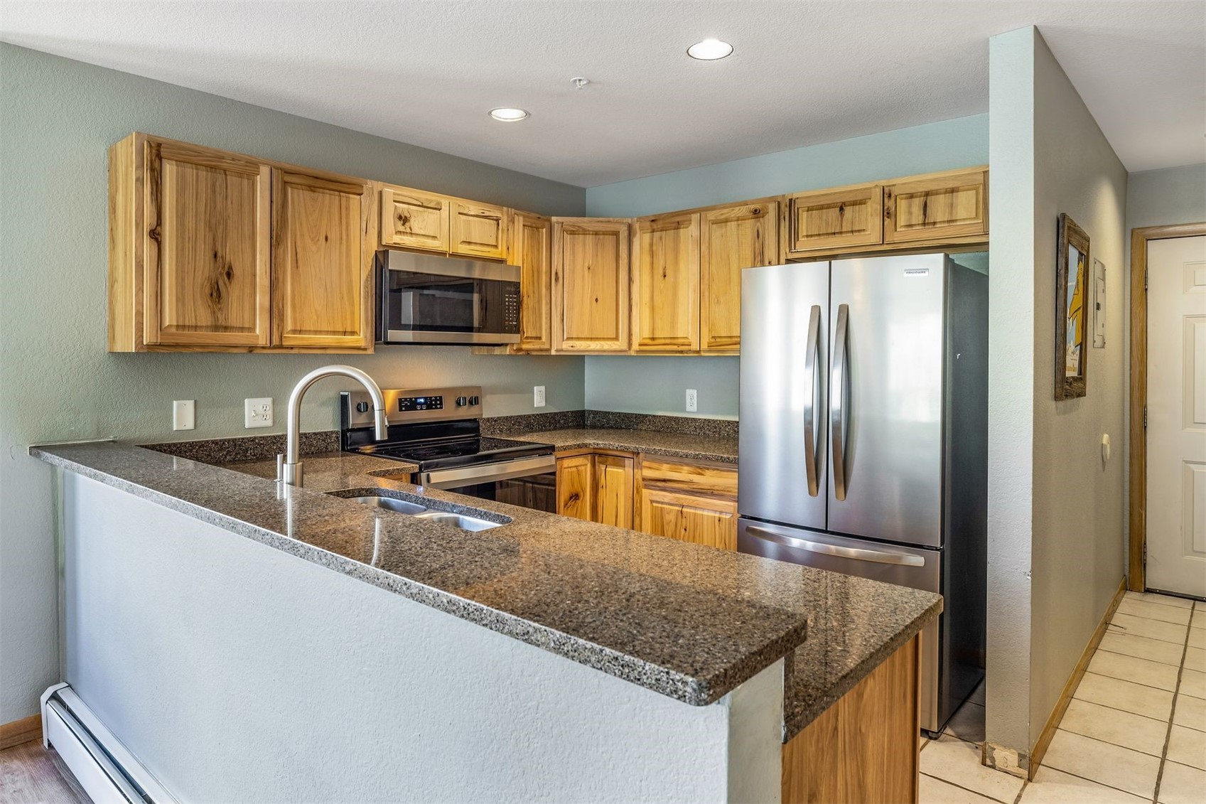 60 Oro Grande Road, Unit 204 Keystone, CO 80435 - Photo 9 of 50 a kitchen with granite countertop a refrigerator a sink a stove a microwave and wooden cabinets