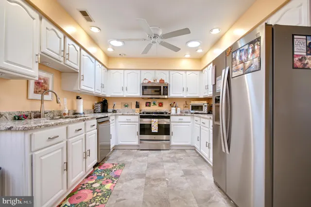 a kitchen with stainless steel appliances kitchen island granite countertop a refrigerator and cabinets