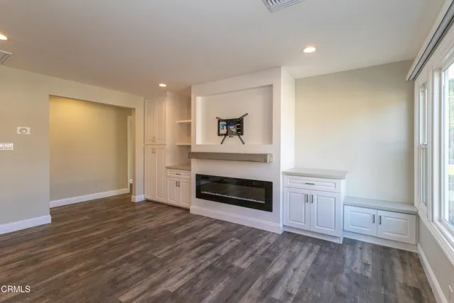 an empty room with wooden floor fireplace and windows