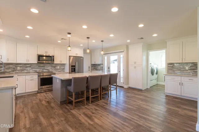 a kitchen with kitchen island white cabinets and stainless steel appliances