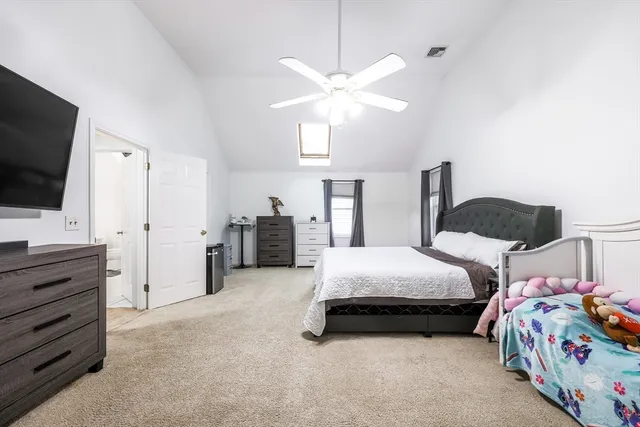 a spacious bedroom with a bed and a flat tv screen on dresser