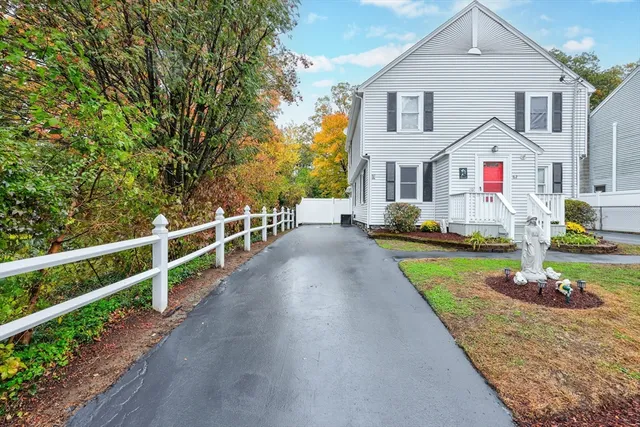 a view of a white house with a small yard and wooden fence