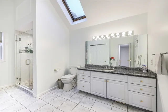 a spacious bathroom with a granite countertop sink a toilet and a mirror