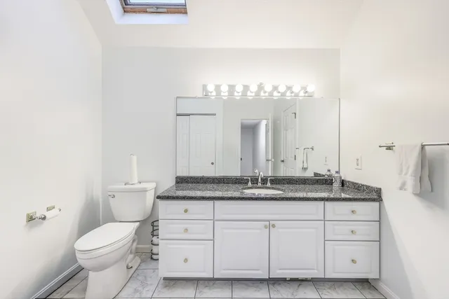 a bathroom with a granite countertop toilet sink and mirror