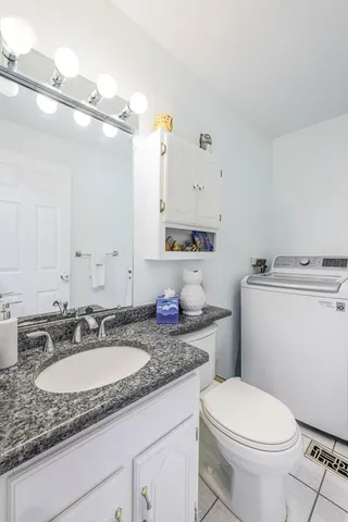 a bathroom with a granite countertop sink a mirror and a toilet