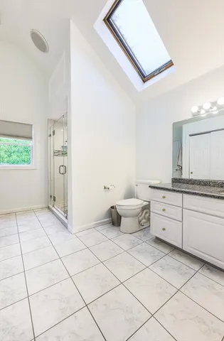 a spacious bathroom with a granite countertop sink a toilet and mirror