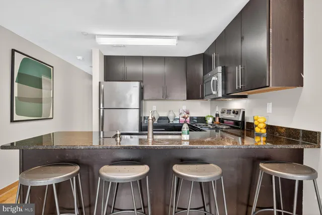 a kitchen with stainless steel appliances granite countertop a table chairs a sink and dishwasher