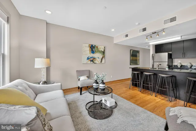 a living room with furniture kitchen view and a wooden floor