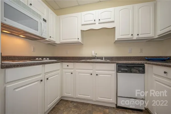 a kitchen with white cabinets and sink