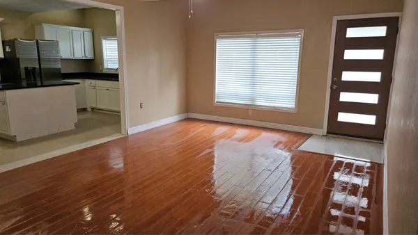 an empty room with wooden floor and windows