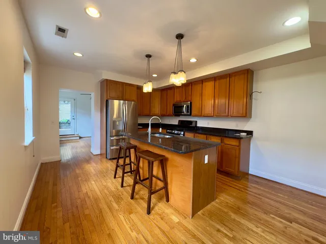 a kitchen with stainless steel appliances granite countertop a sink a stove a refrigerator cabinets and wooden floor