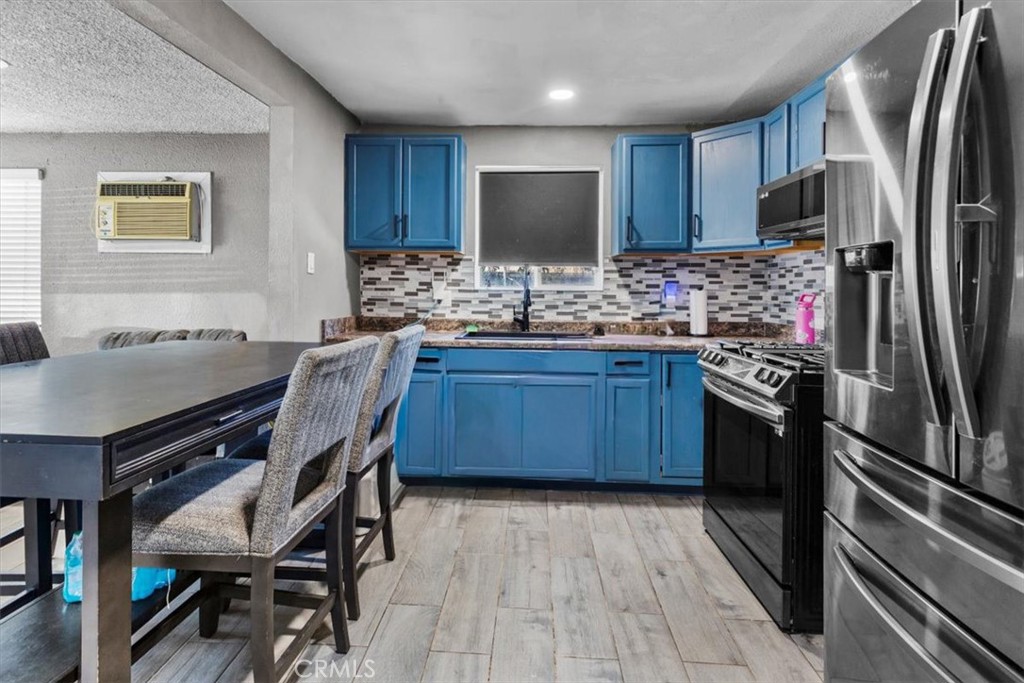 3715 South Neece Street Corona, CA 92879 - Photo 8 of 20 a kitchen with stainless steel appliances granite countertop a stove refrigerator a sink dishwasher a dining table and chairs with wooden floor