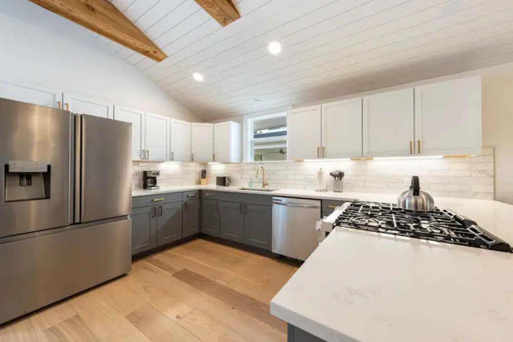 2319 Santa Rita Street Austin, TX 78702 - Photo 5 of 26 Dual tone kitchen with two tone cabinetry, stainless steel appliances, recessed lighting, light wood-type flooring, and tasteful backsplash