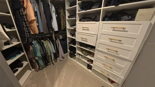 a view of walk in closet with clothes and shoes