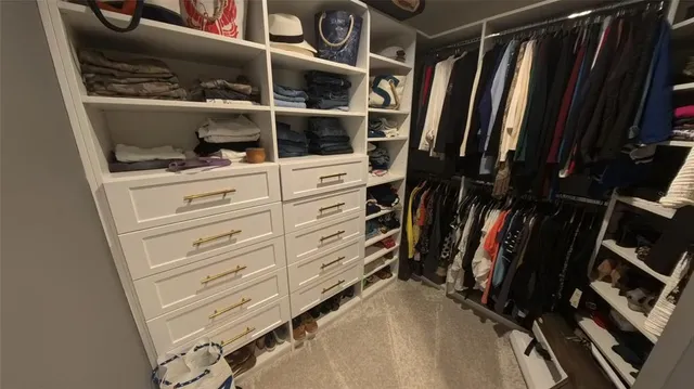 a view of walk in closet with clothes and shoes