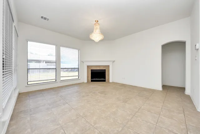 an empty room with windows and fireplace