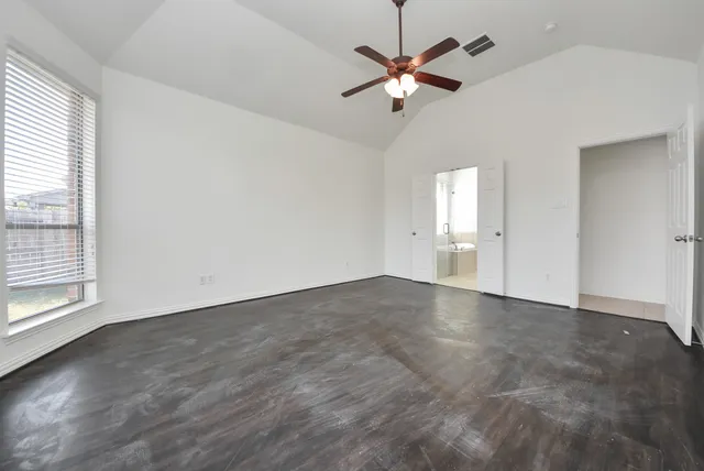 an empty room with chandelier fan and windows