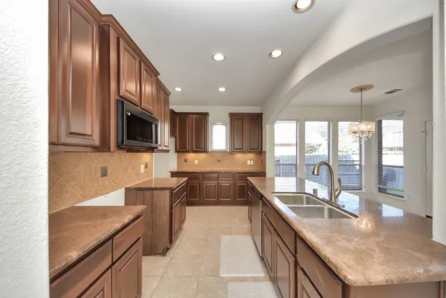 a large kitchen with granite countertop a large counter top stainless steel appliances a sink and cabinets