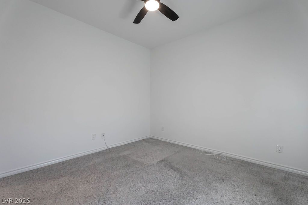 7126 Calvert Cliffs Street North Las Vegas, NV 89084 - Photo 33 of 44 A well-lit bedroom with neutral carpet and a ceiling fan, offering a clean canvas for personalized comfort.