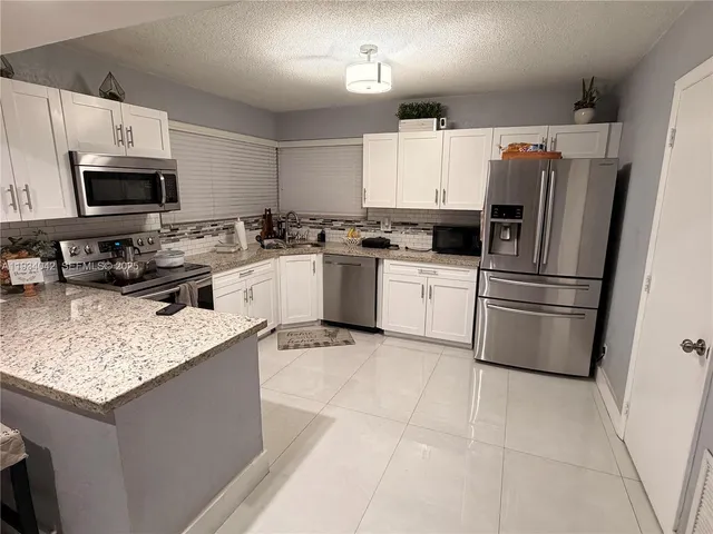a kitchen with stainless steel appliances granite countertop a refrigerator stove microwave and sink