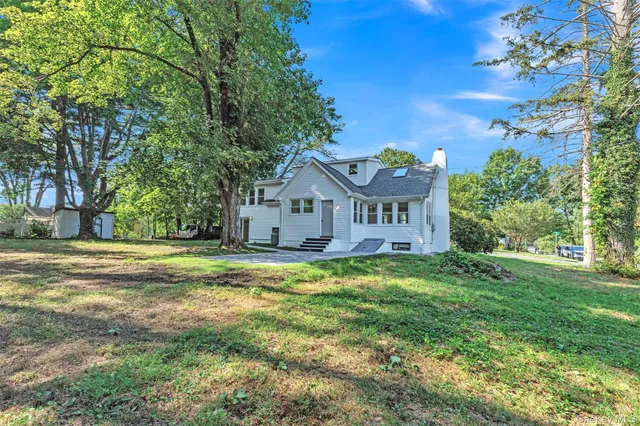 a view of a house with a big yard and large trees