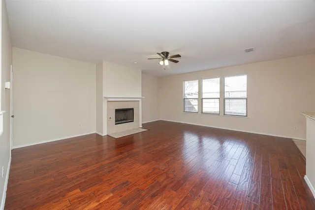 an empty room with wooden floor fireplace and windows