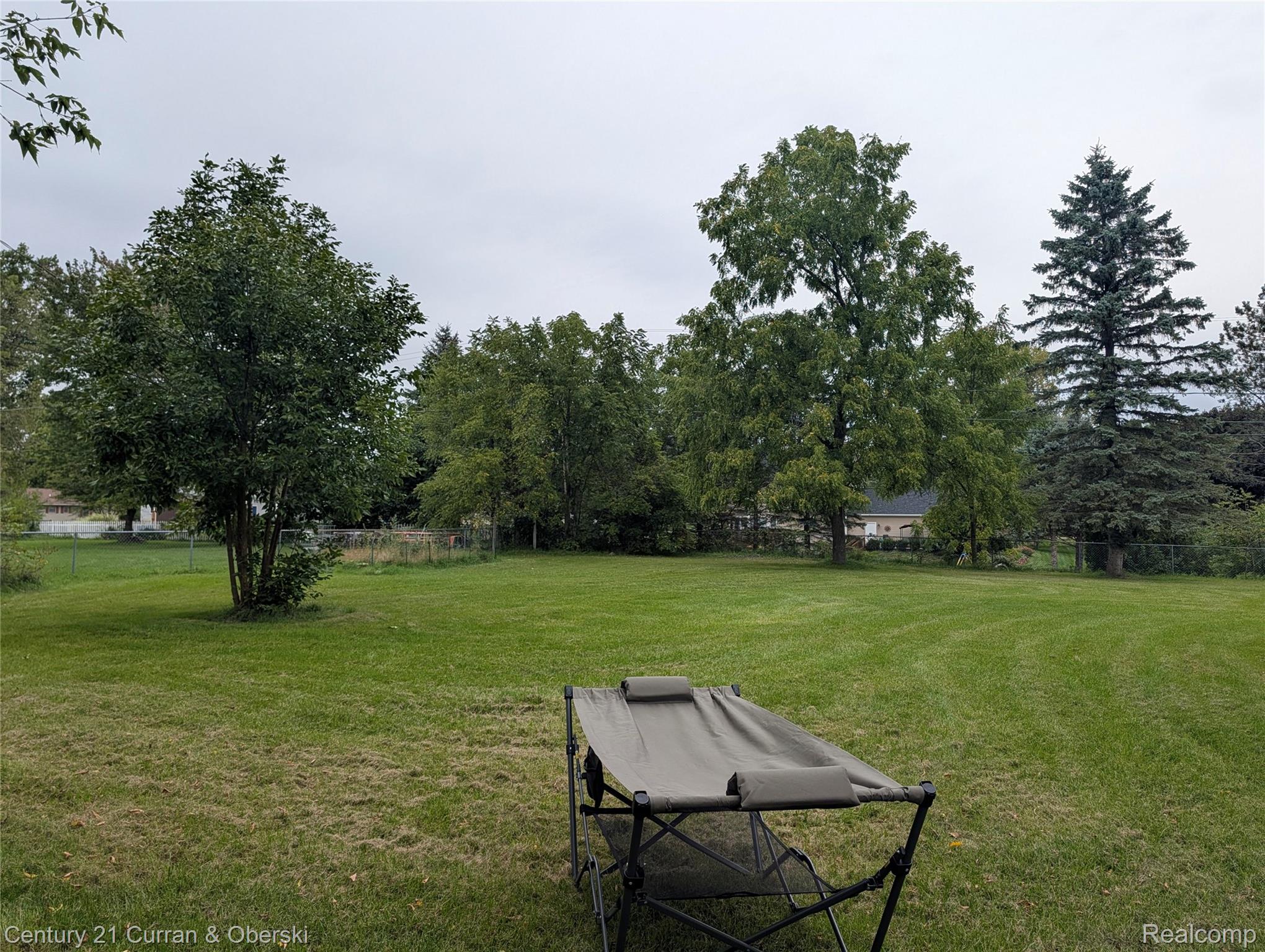 9371 Bennett Lake Road Fenton, MI 48430 - Photo 4 of 17 Expansive green lawn with mature trees and perimeter fencing