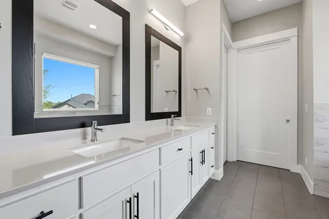 a bathroom with double vanity and a mirror